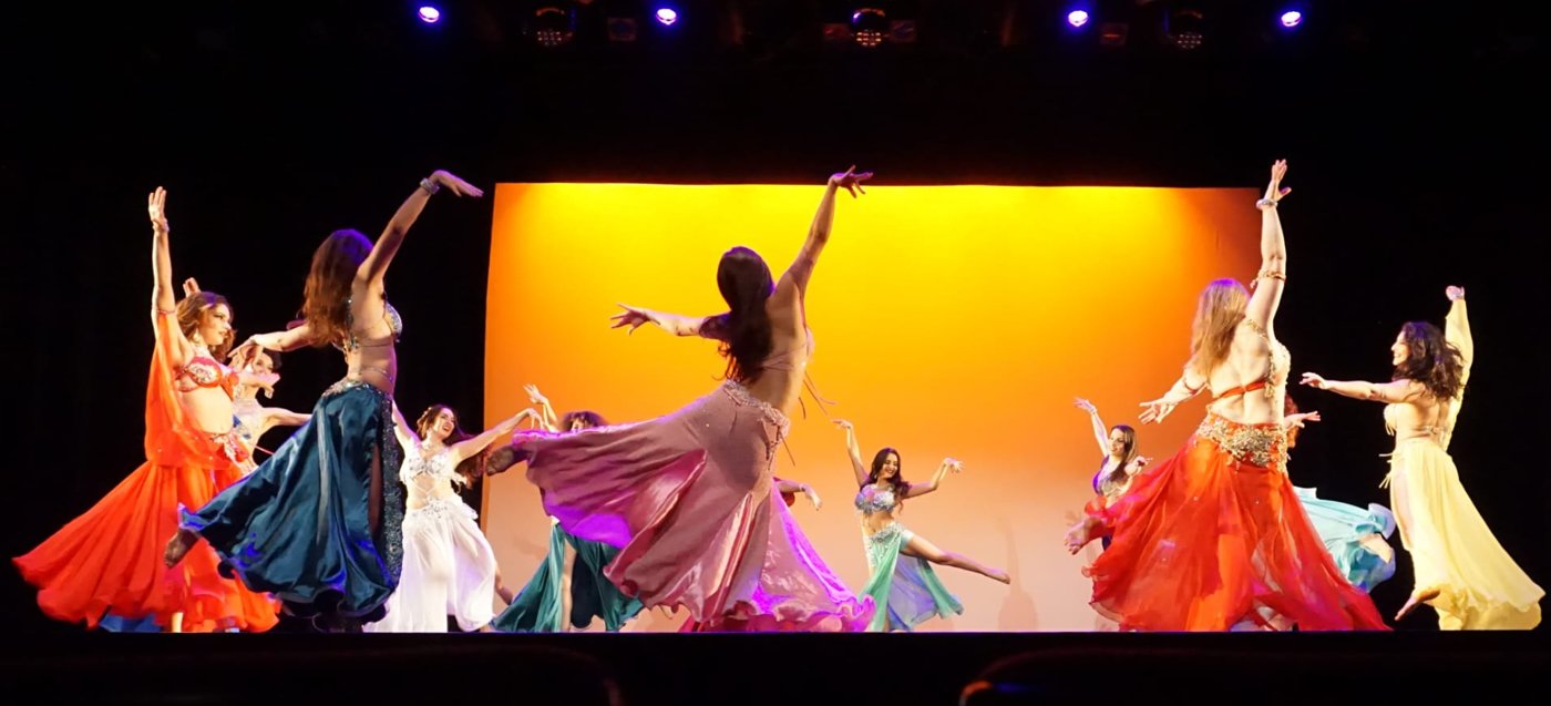 Les danseuses du Ballet Egypt'Ciya tournent dans leurs jupes colorées devant un fond orangé