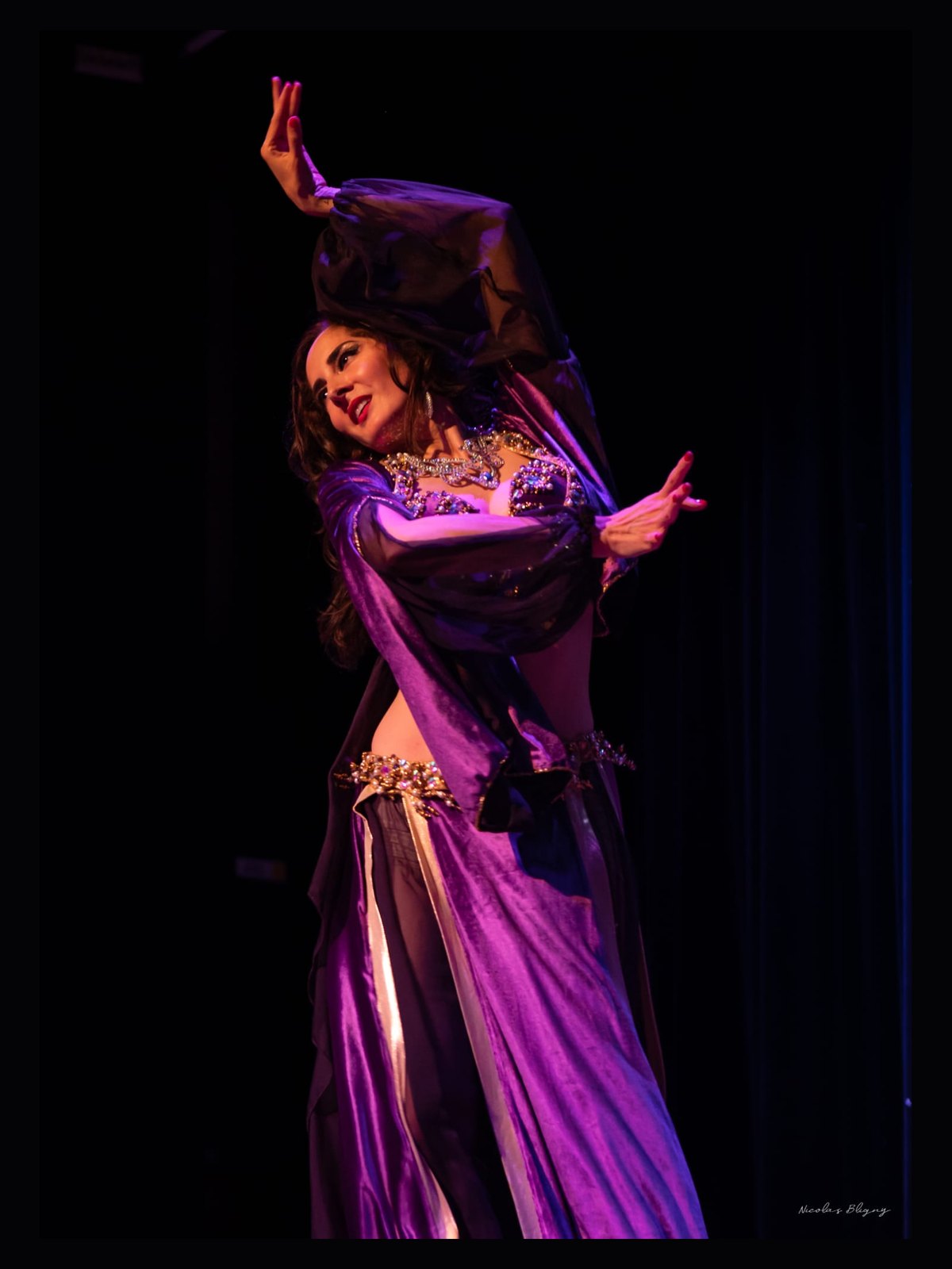 Ciya en costume violet, bras levé dans un voile, sur scène